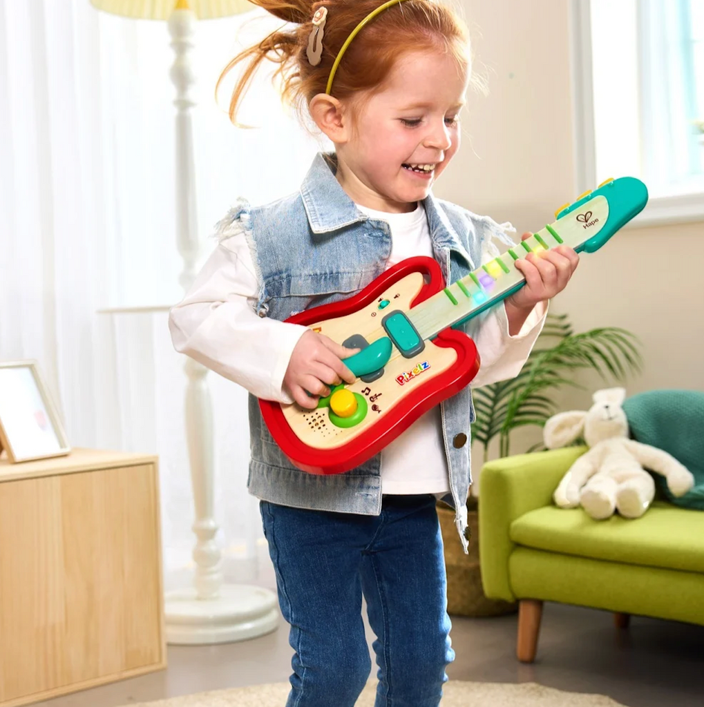 A young child playing the Rainbow Rock Pixel Guitar by pushing the fret buttons and moving the whammy bar. 