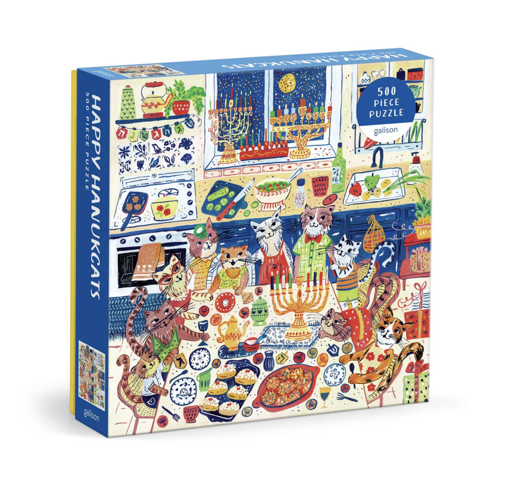Happy Hanukcats 500 piece puzzle box cover with an illustrated image of a cat family surrounding a table full of traditional Hanukkah dishes, toys and a menorah. 