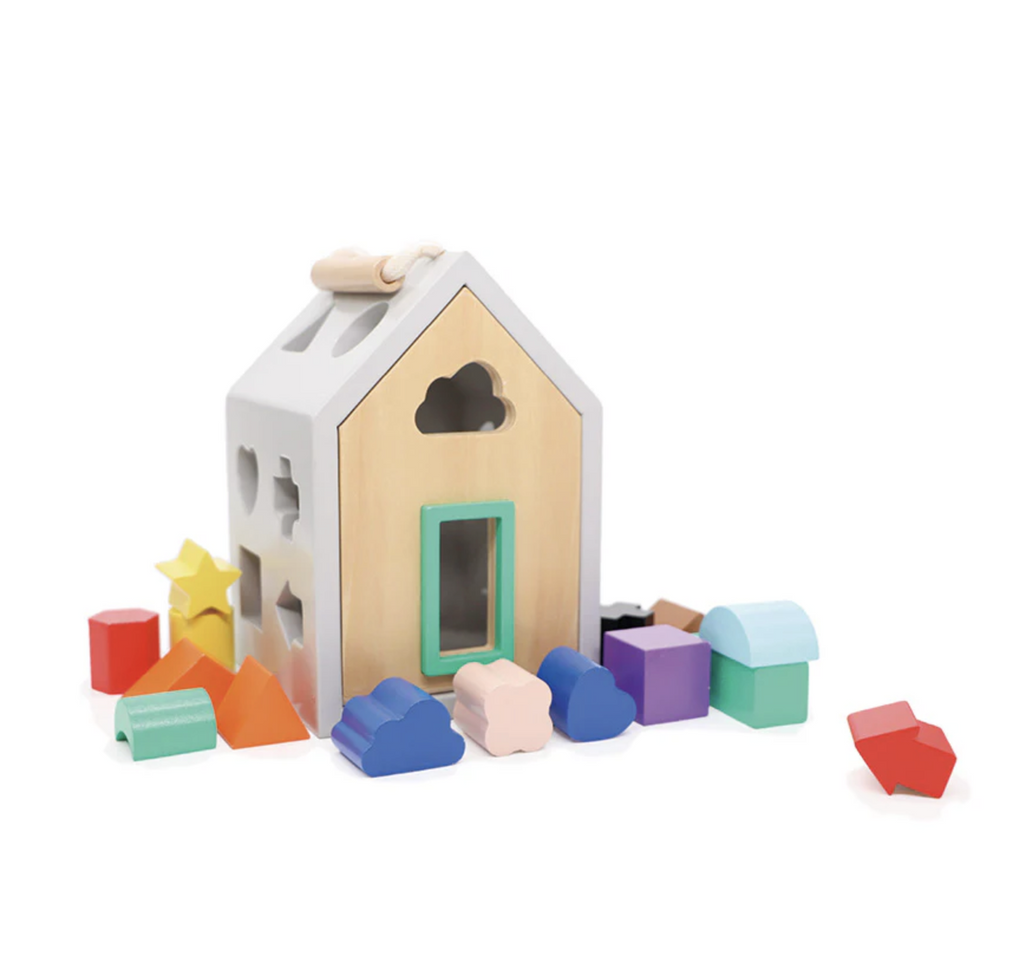 A house shaped box with different shaped holes cut out of all sides and a handle on top. Brightly colored wooden shapes are placed around the box. 