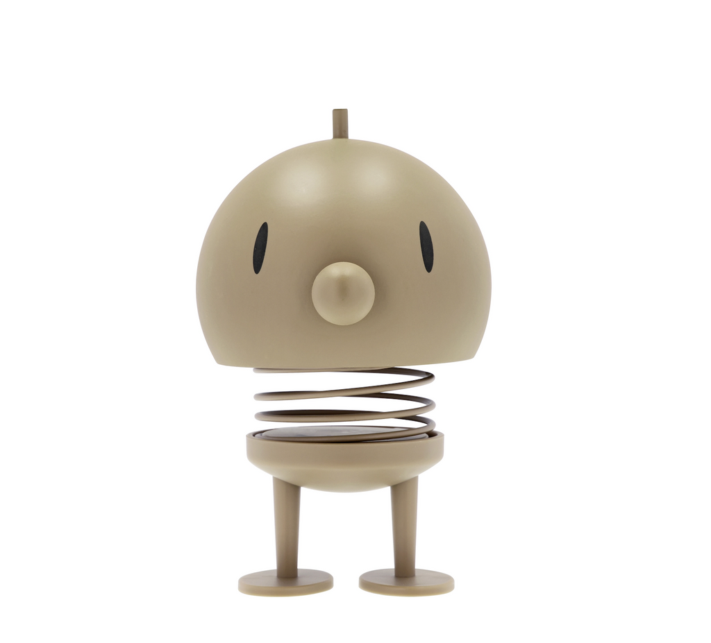 Latte colored large Hoptimist which is a round head with friendly eyes and nose on a spring that has legs. 