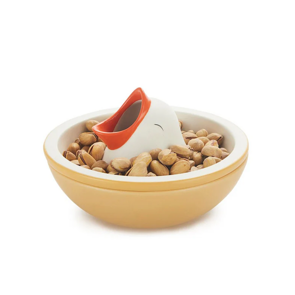 The Hungry Bird Snack Bowl loaded up with pistachios so that the ceramic bird looks like it is emerging from under the pistachios. 