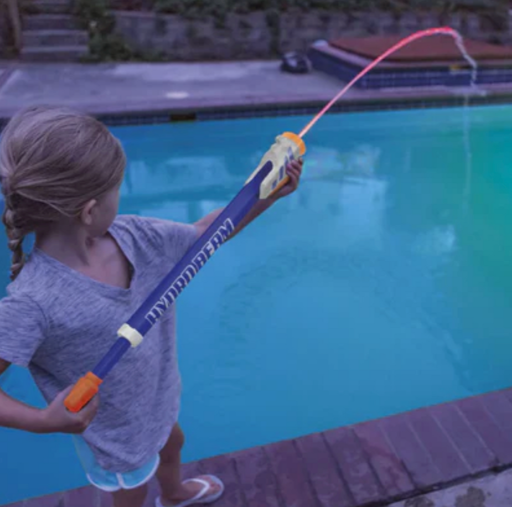 A kid launching a pink blast of water into a pool. 