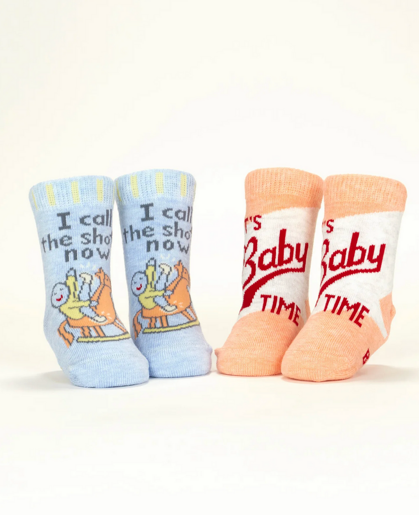 Two pair of infant socks displayed on mannequin feet. One pair is light blue and reads "I call the shots now" while the other pair are peach and white and read "It's Baby Time" 