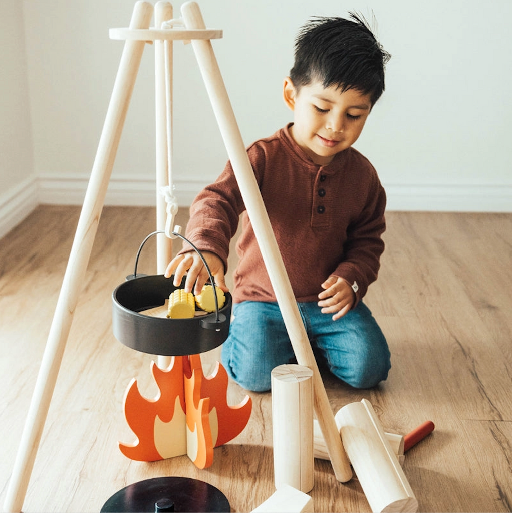 A young child loading up the cooking pot with the toy food that comes with the Home On the Range toy cooking set. 