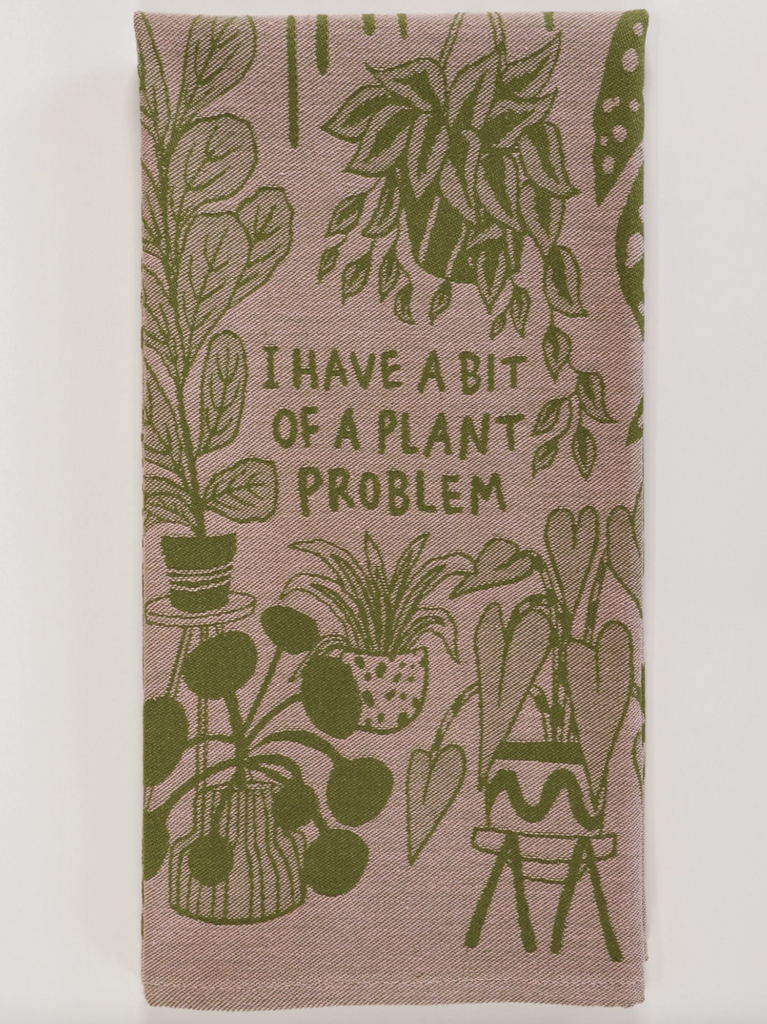 Folded dish towel with green graphics of all sorts of plants. That reads "I Have A Bit Of A Plant Problem"