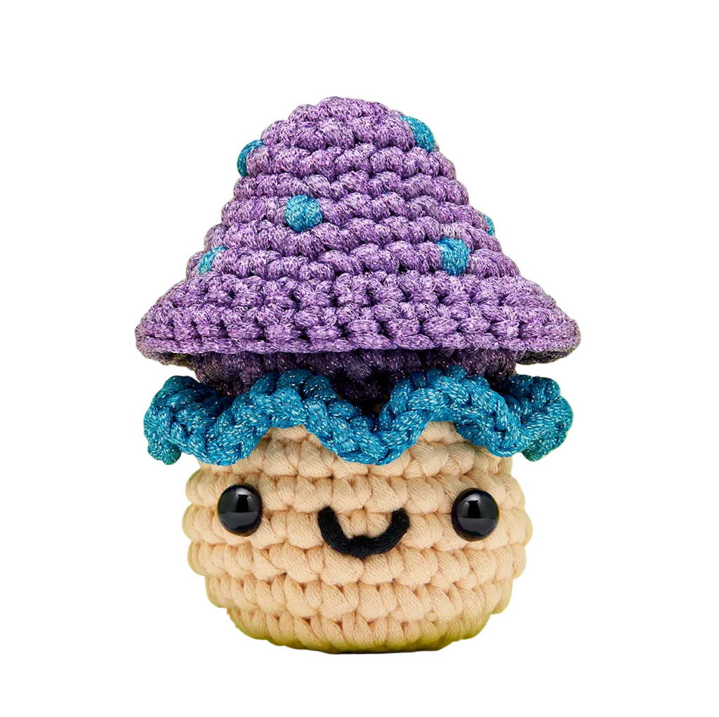 Crocheted character of a Irving the Mushroom with a purple hat and blue trim. 