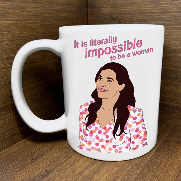White ceramic mug with illustrated image of Gloria, America Ferrera's character from the Barbie movie with the quote "It is literally impossible to be a woman."