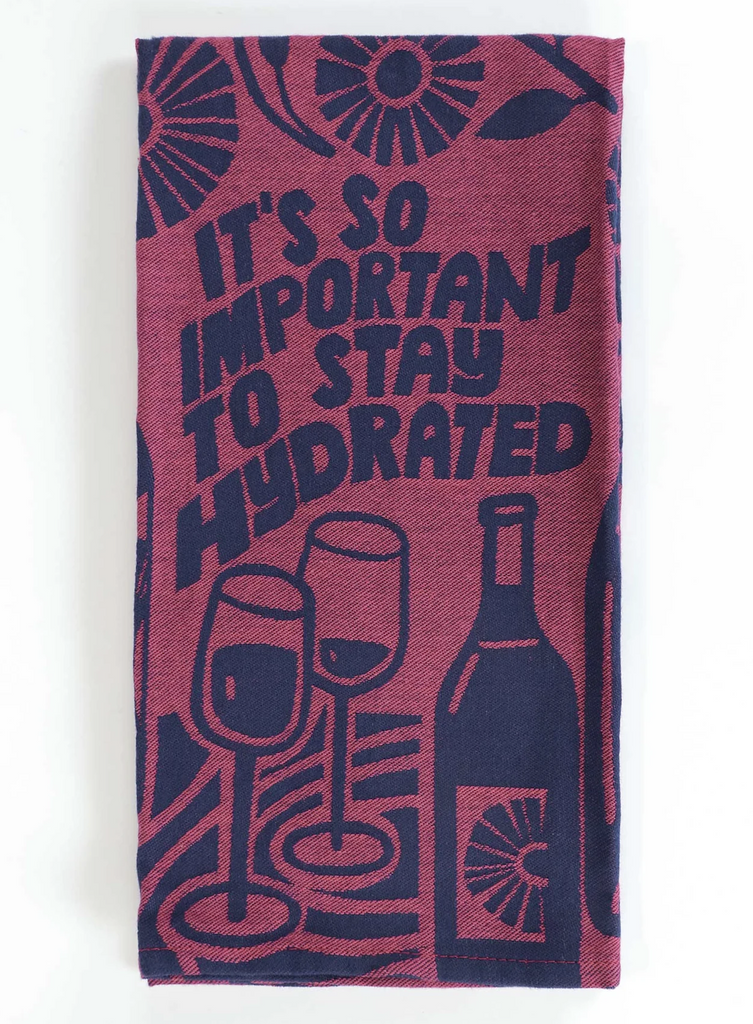 Maroon colored woven dish towel with images of blue wine bottles, glasses and flowers. it reads "It's So Important To Stay Hydrated"