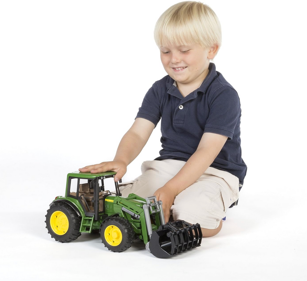 A child sitting on the floor playing with the John Deere 6920 with Front Loader toy tractor. 