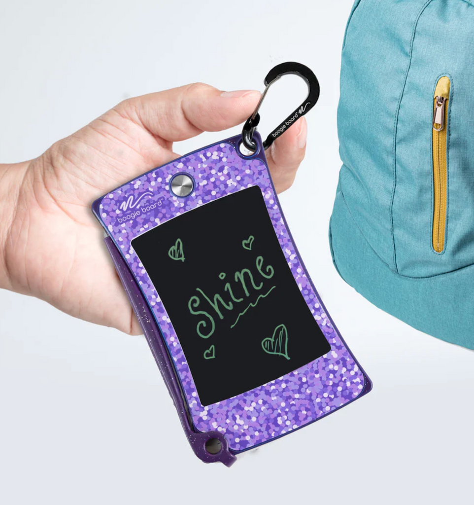 The Jot Pocket Writing Tablet in Shimmer Purple being clipped to  a backpack. 