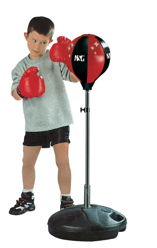 A kid all set up wearing the boxing gloves and punching the free standing punching bag. 