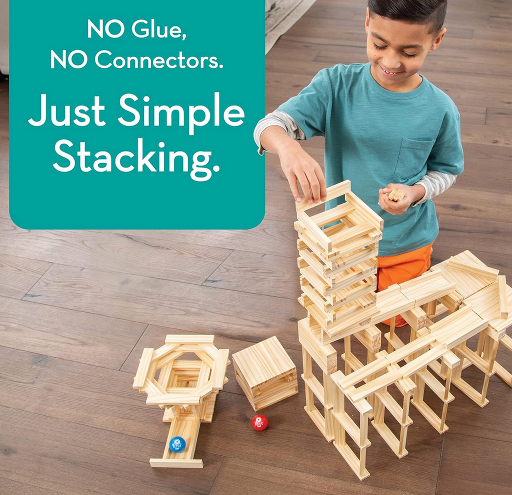 A young child building a structure of slopes and towers using the KEVA Contraptions set. A caption that reads "No glue, no connectors, just simple stacking" is in thr top left corner.