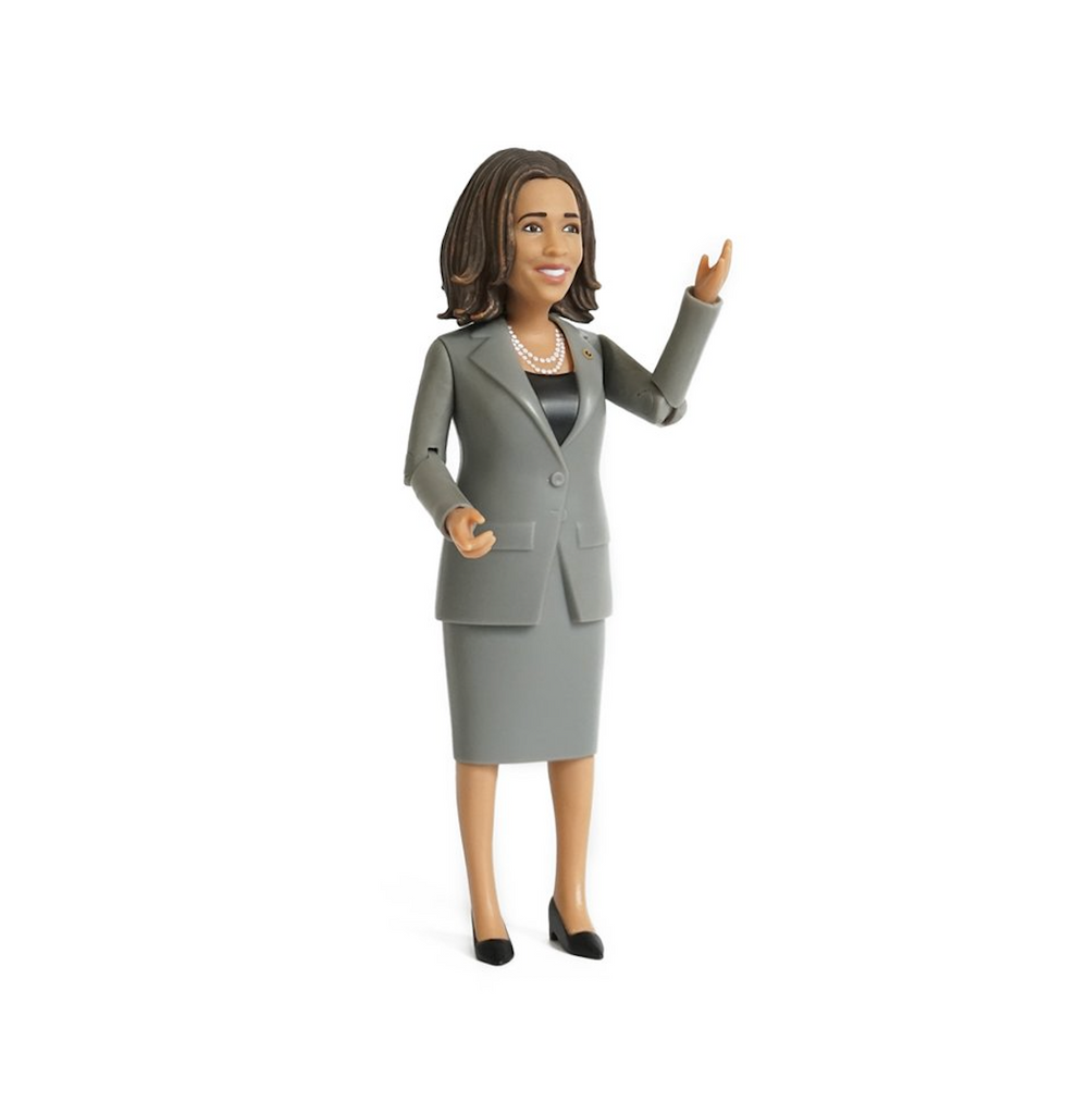 Kamala Harris action figure with her and raised as if saying "Hello"