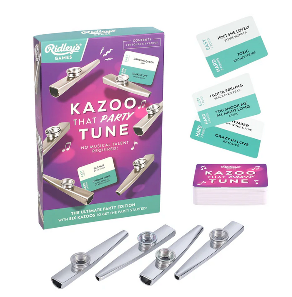 Kazoo That Party Tune game box in the corner with cards from the game with song suggestions and four silver kazoos in the foreground. 