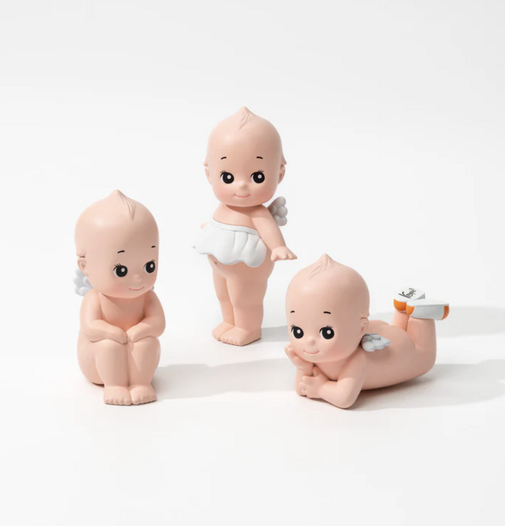 Three styles of Kewpie doll blind box figures. One sitting, one is standing, one laying on its stomach with chin in hand.