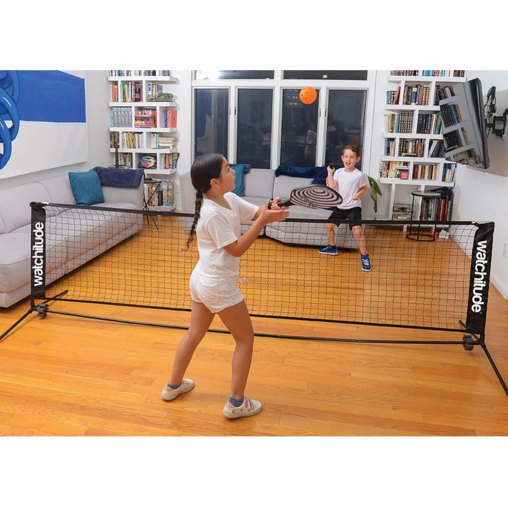 Kids playing indoor pickleball in a living room.