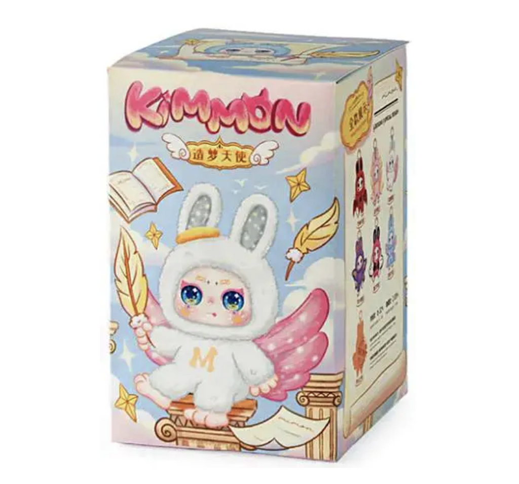 Box with colorful illustration of a Kimmon Dream Maker doll with white plush fur, bunny ears with a gold halo draped over an ear and pink wings. On the side of the box we can see that there are illustrations of each of the figures in the series. 