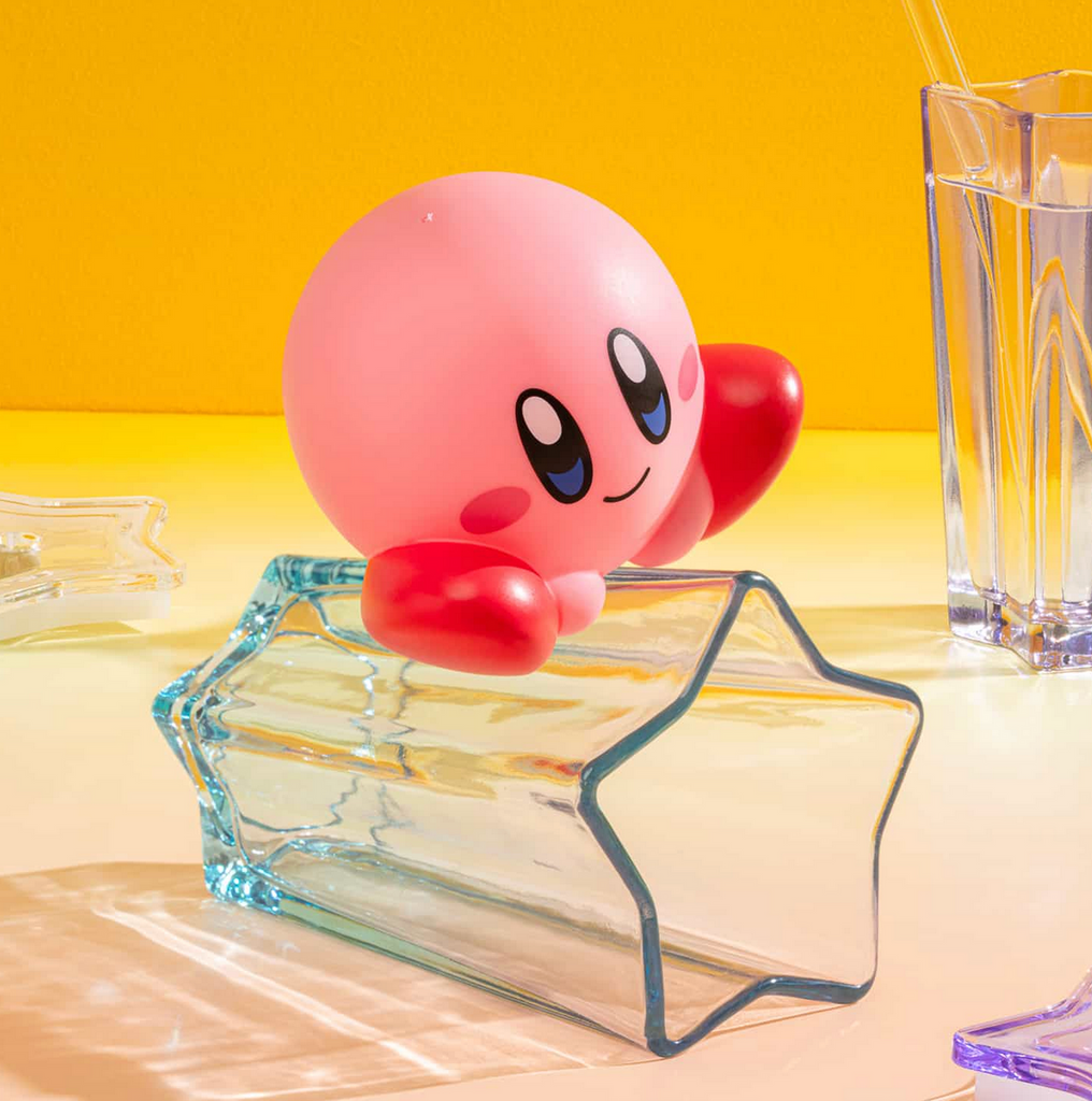 Kirby figure sitting on a star shpaed glass vase on a yellow background.