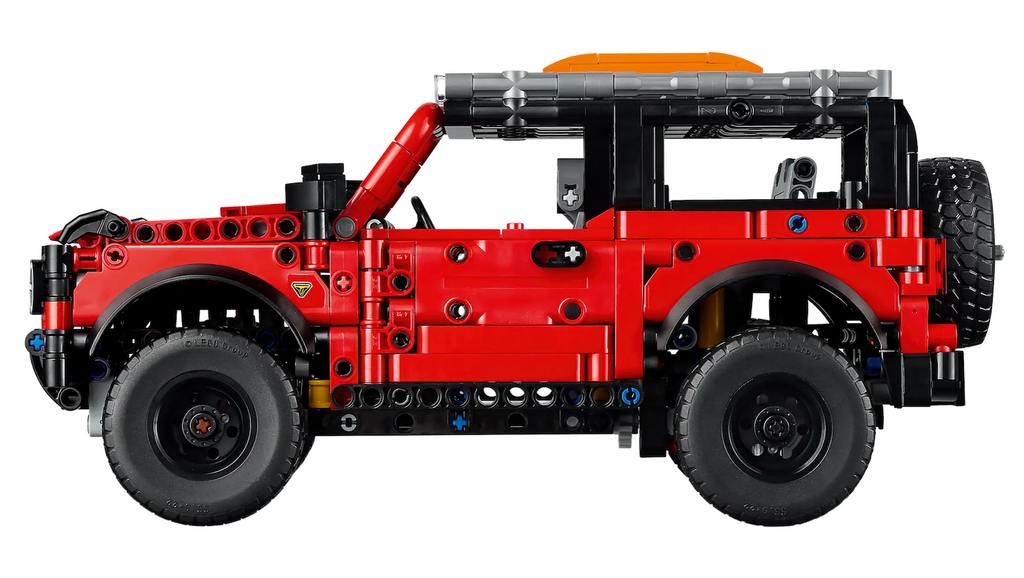 SIde view of the red and black Ford Bronco LEGO vehicle model made of interlocking LEGO bricks featuring realistic details including opening doors and suspension with a front axle and a live rear axle. 