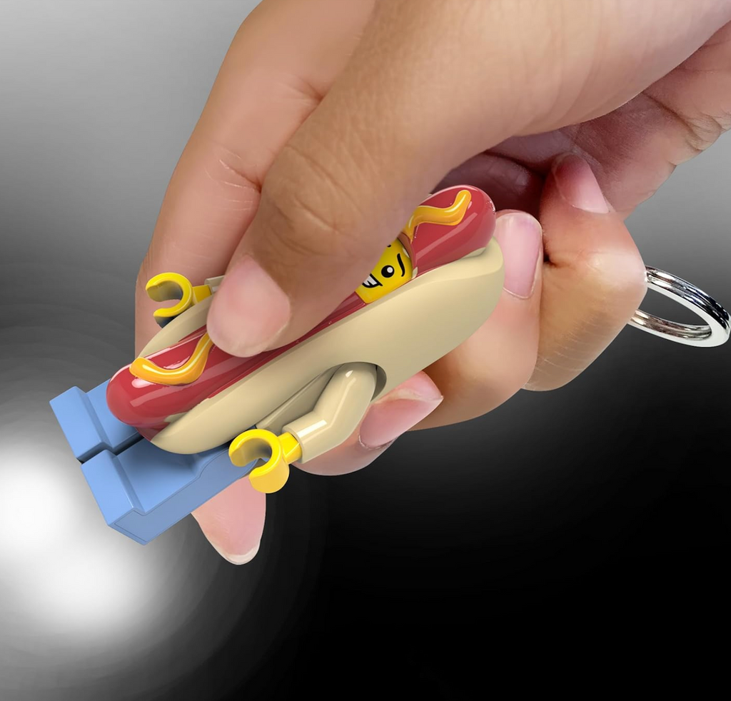 The LEGO LED Hot Dog Guy minfigure keychain held and pressed to shine the light out of his feet. 