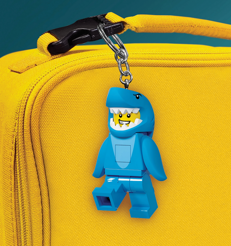 The LEGO LED Keychain Shark Suit attached to the handle of a yellow backpack. 
