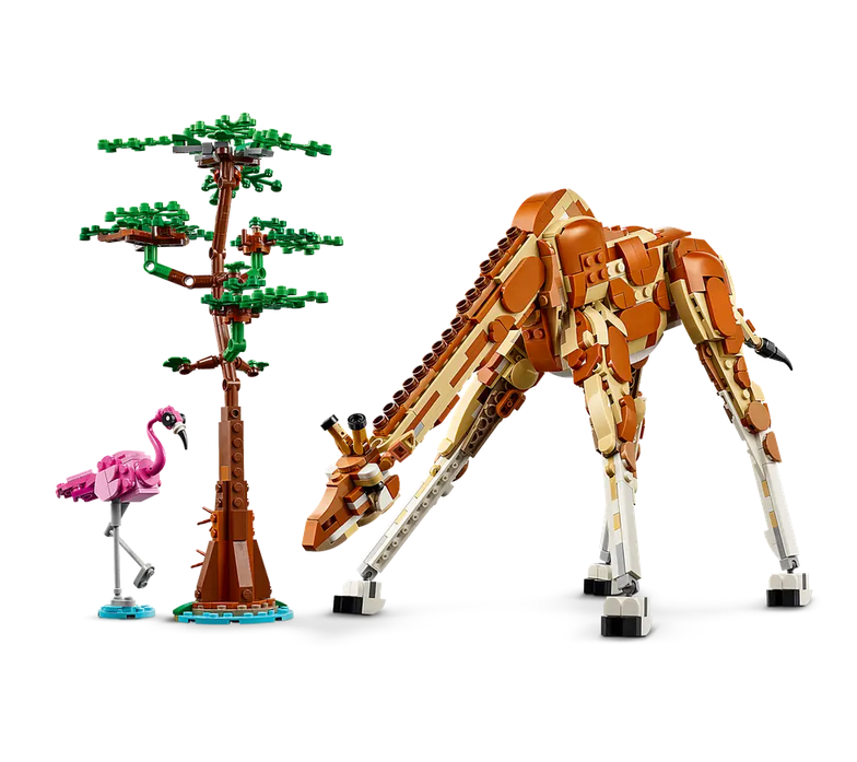 The giraffe toy with posable legs, long neck, tail and ears, standing next to a small brick-built tree and a flamingo toy.