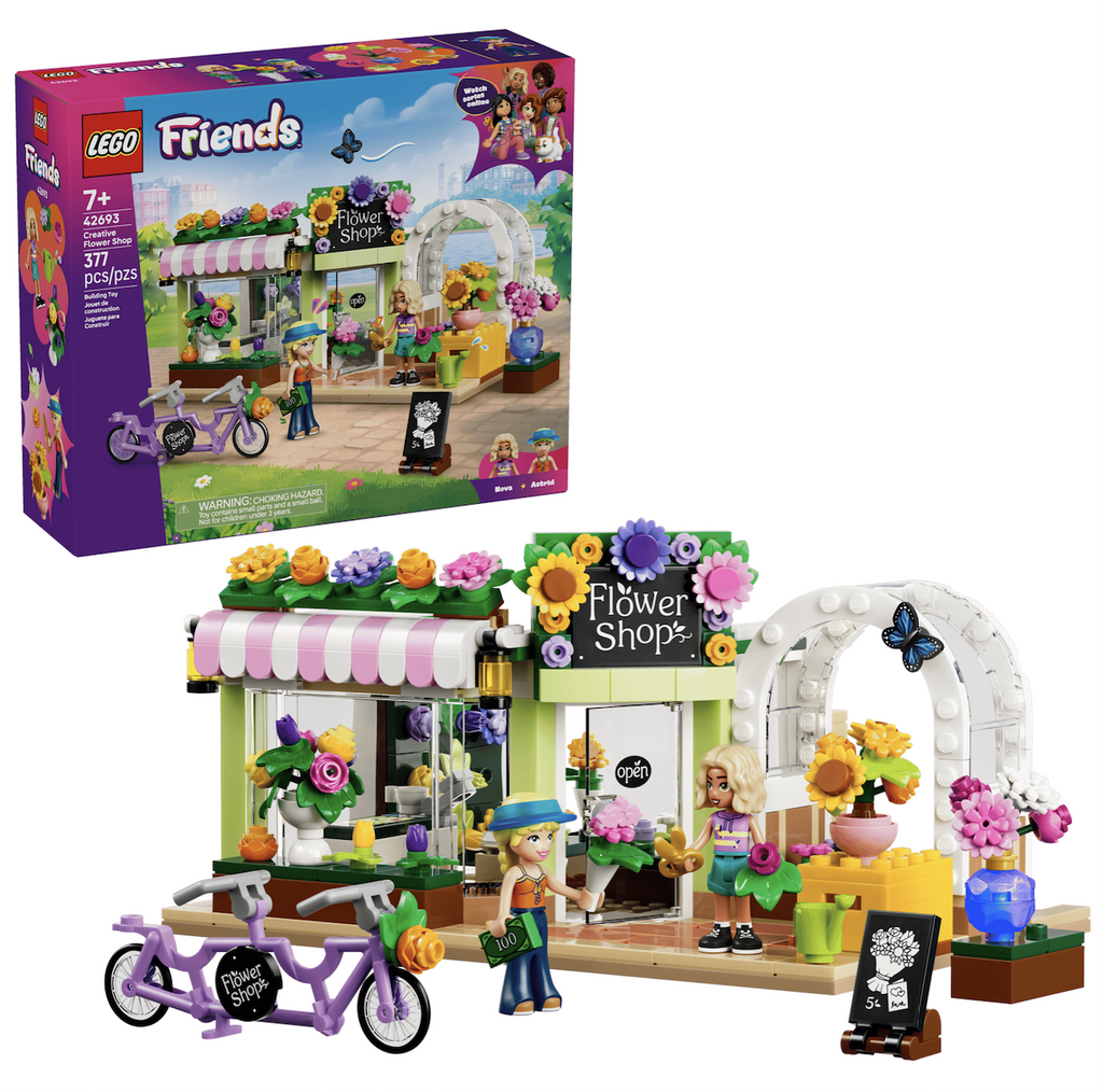 Box for LEGO Friends Creative Flower Shop in the background with the set fully constructed with the minidolls Nova and Astrid placed in the flower shop and the tandem bicycle sitting outside. 