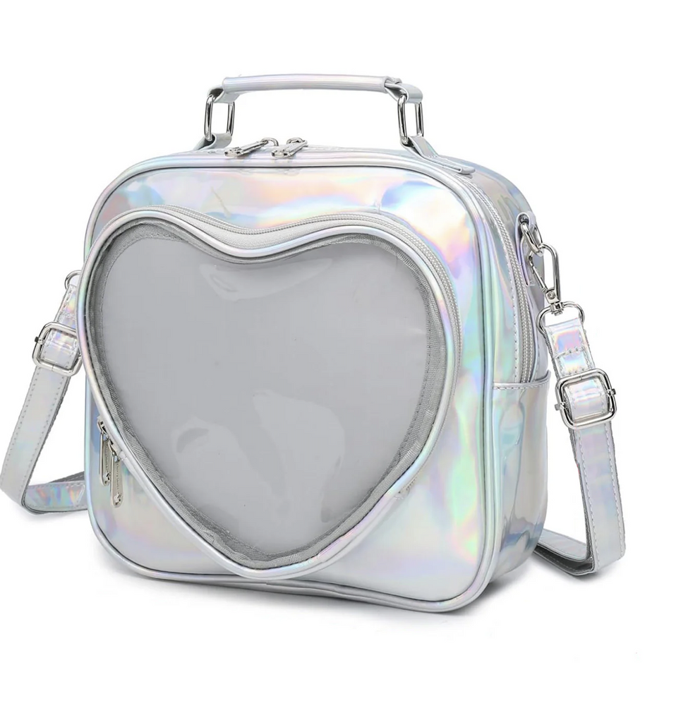 Square shaped purse with handle on top that has a clear heart shaped pocket on the front and silver, iridescent material over the rest of the bag and strap. 