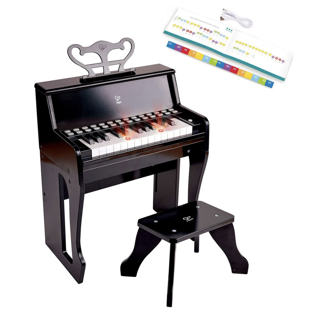 Black toy piano with matching stool. A few of the white keys are illuminated to help the child follow along and learn to play. In the top right hand corner of the picture the USB cord, song book and color coded key chart are pictured. 