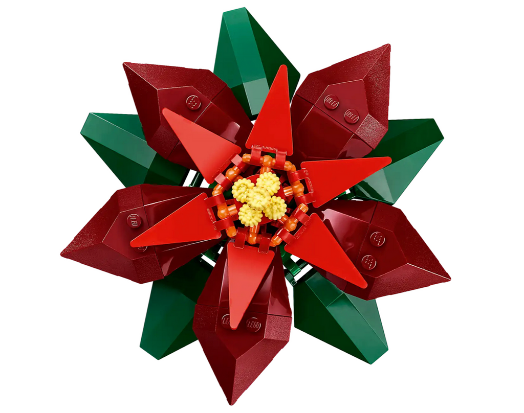 Close up top view of a poinsettia blossom built out of legos, with contrasting red petals and green leaves. 