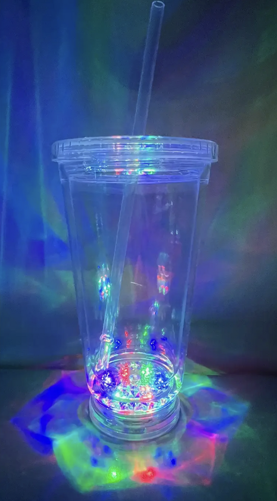 Clear plastic tumbler with straw and multi color lights in the bottom. 