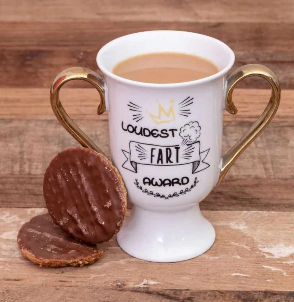 The "Loudest Fart Award" trophy mug filled with coffee and cookie beside it.