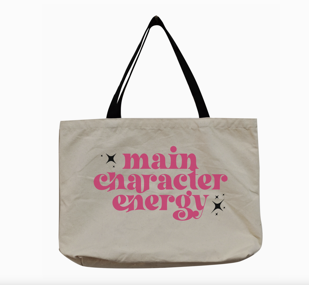 Oversized canvas  tote bag with long black fabric handles. Hot pink text reads "Main Character Energy". 
