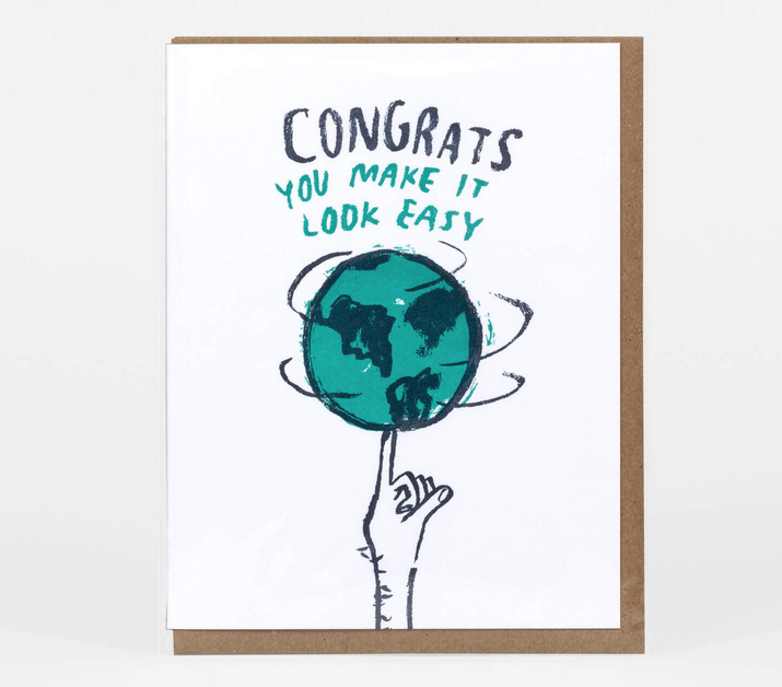 Greeting card with illustrated image of a globe spinning on a finger that reads "Congrats You Make It look Easy"