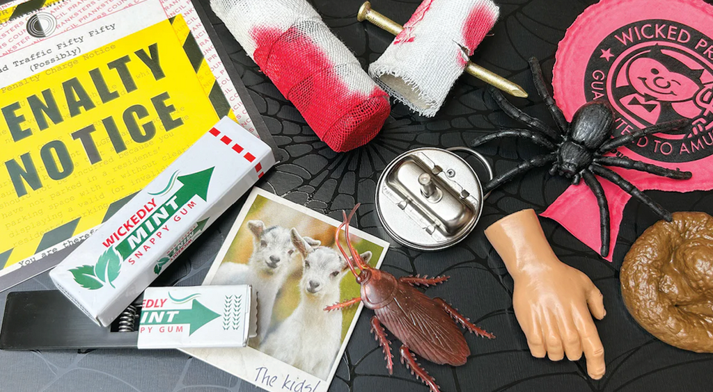 Assorted pranks and trick items including a spider, novelty items, and a 'Penalty Notice' sign on a black surface.