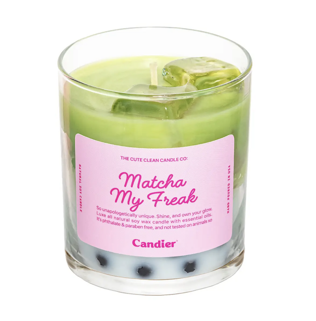 Clear glass jar candle filled with white and green layered wax made to look like a glass of iced Matcha. A pink label with pink lettering reads Matcha My Freak with a paragraph describing the scent of the candle. 