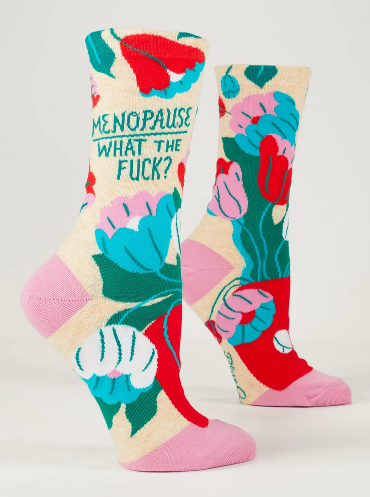 SIde view of crew socks on mannequin feet with bright floral pattern that read "Menopause, What the fuck?"