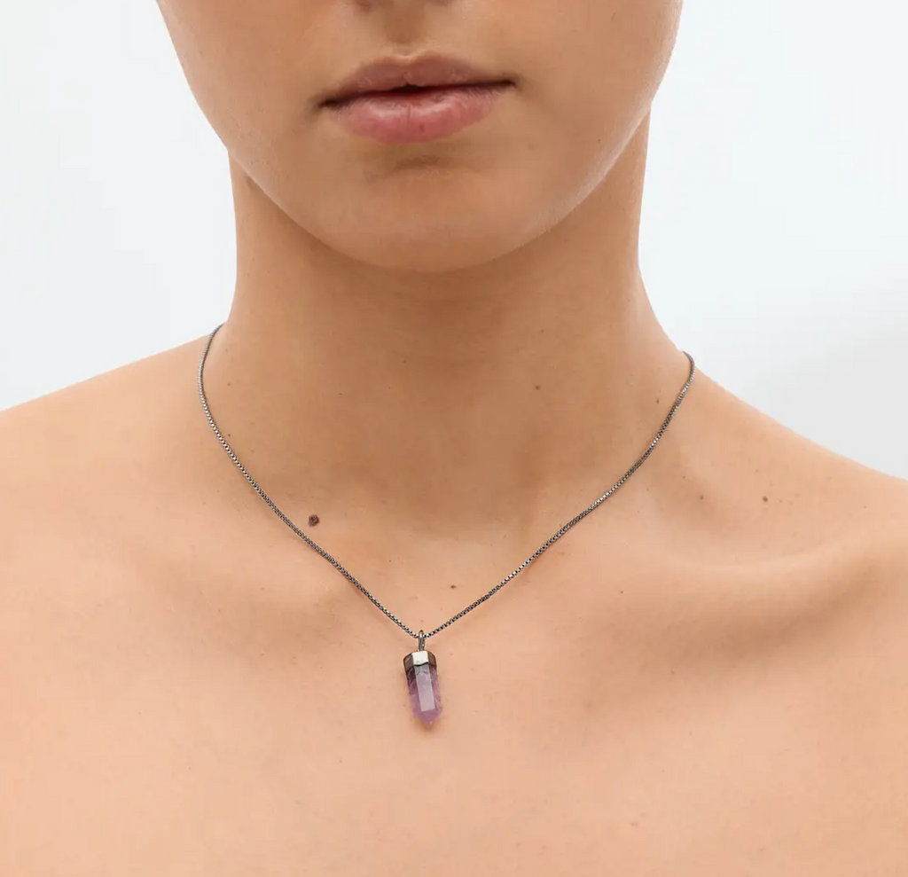 The Mini Amethyst Crystal Pendulum worn around a persons neck. 