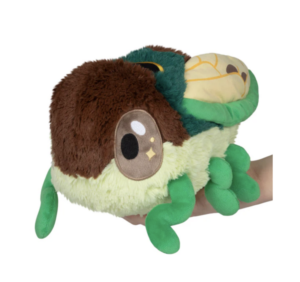 Squishable Mini CIcada stuffed animal perched on a hand with big bug eyes, green legs and beautiful wings. 