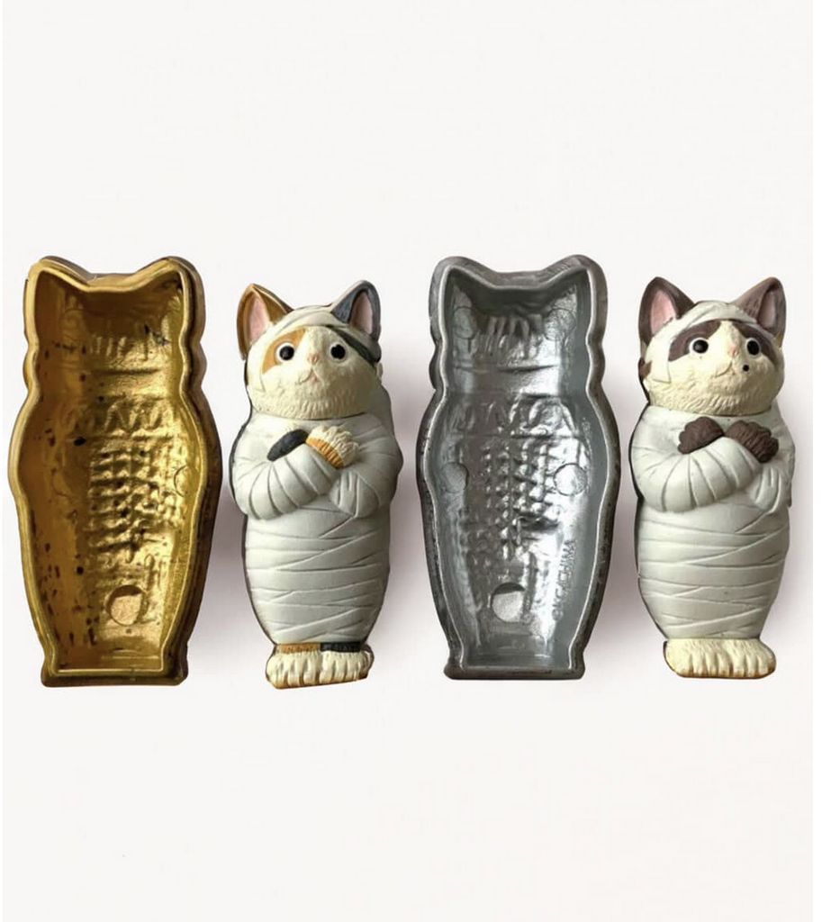 Two Mofusand Mummy Cat vinyl toy figures next to their cat shaped cases.