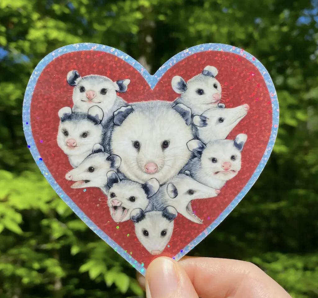 Heart shaped red glitter sticker with an mama opossum surrounded by many babies.