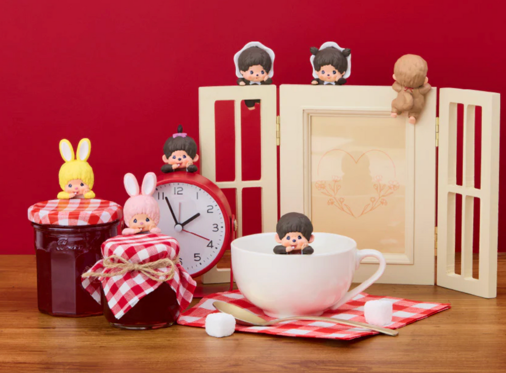 Miniature Monchhichi figures and items on a table with a red background