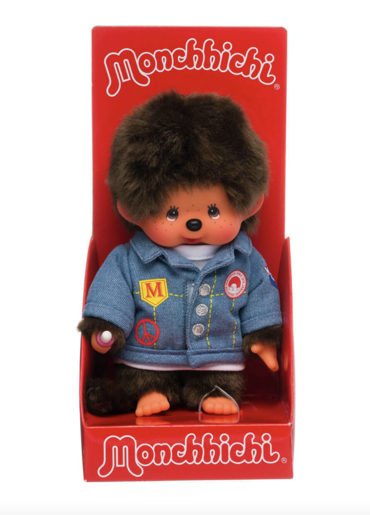 Monchichi doll wearing a denim jacket packaged in an open red box. 