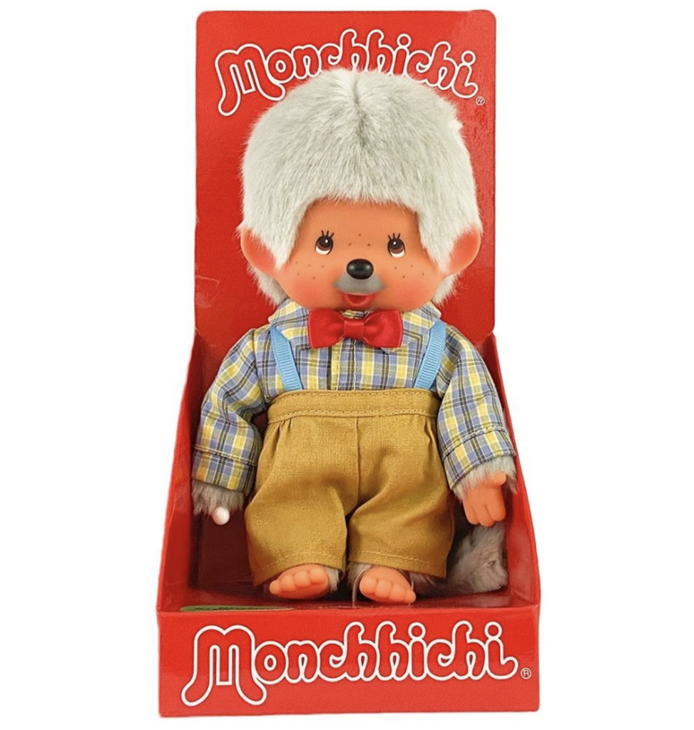 Grandpa Monchhichi plush doll wearing a plaid shirt with trousers and suspenders, packaged in a red box. 