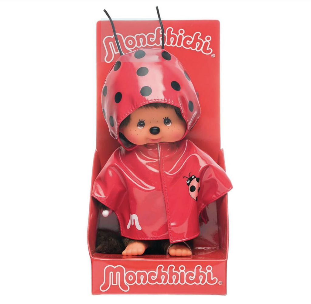Monchhichi doll wearing a red ladybug raincoat with antennae and black polka dots on the hood. 
