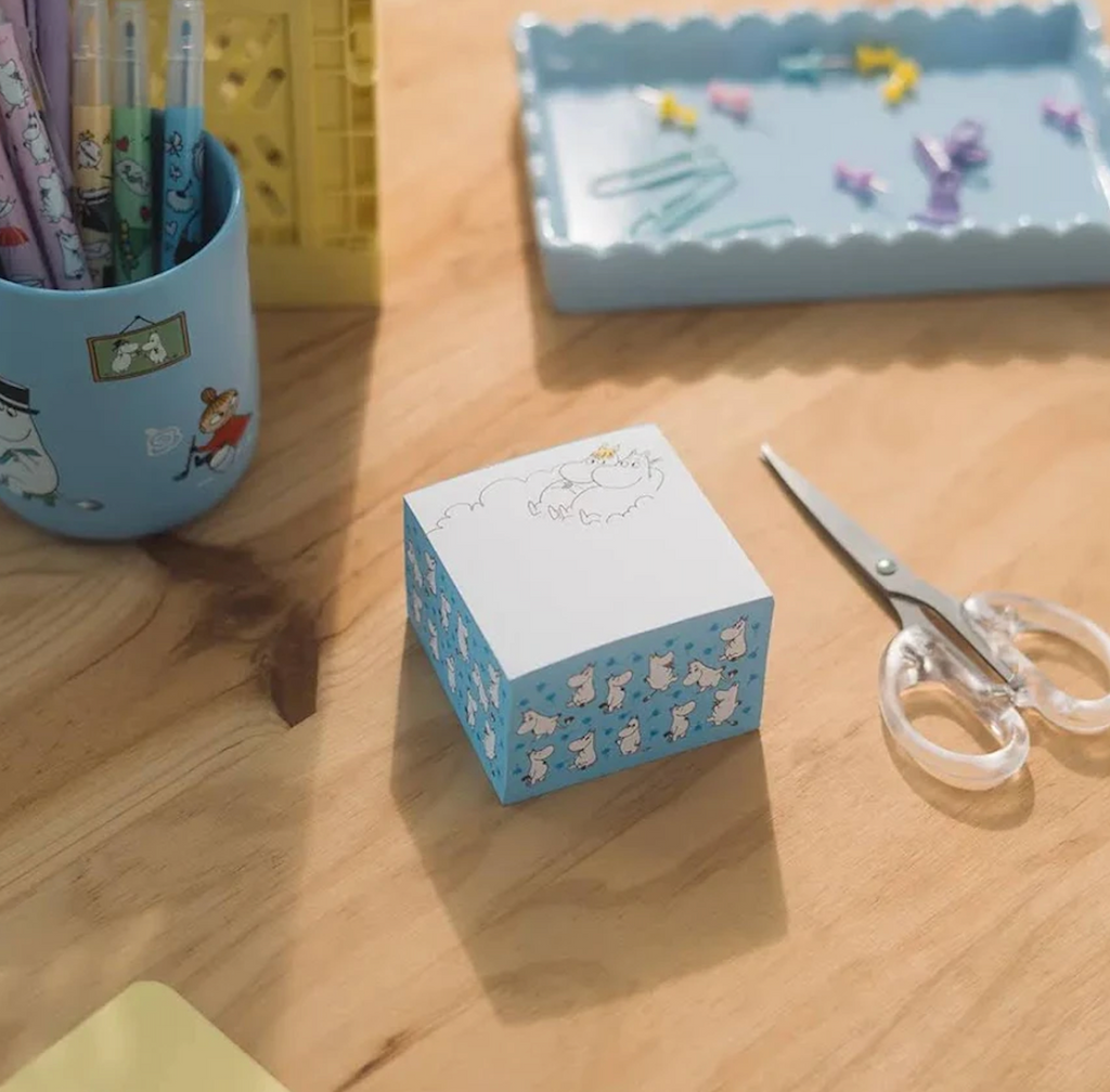 The Moomin Memo Block pictured on a desk alongside scissors, pencils and paperclips. 