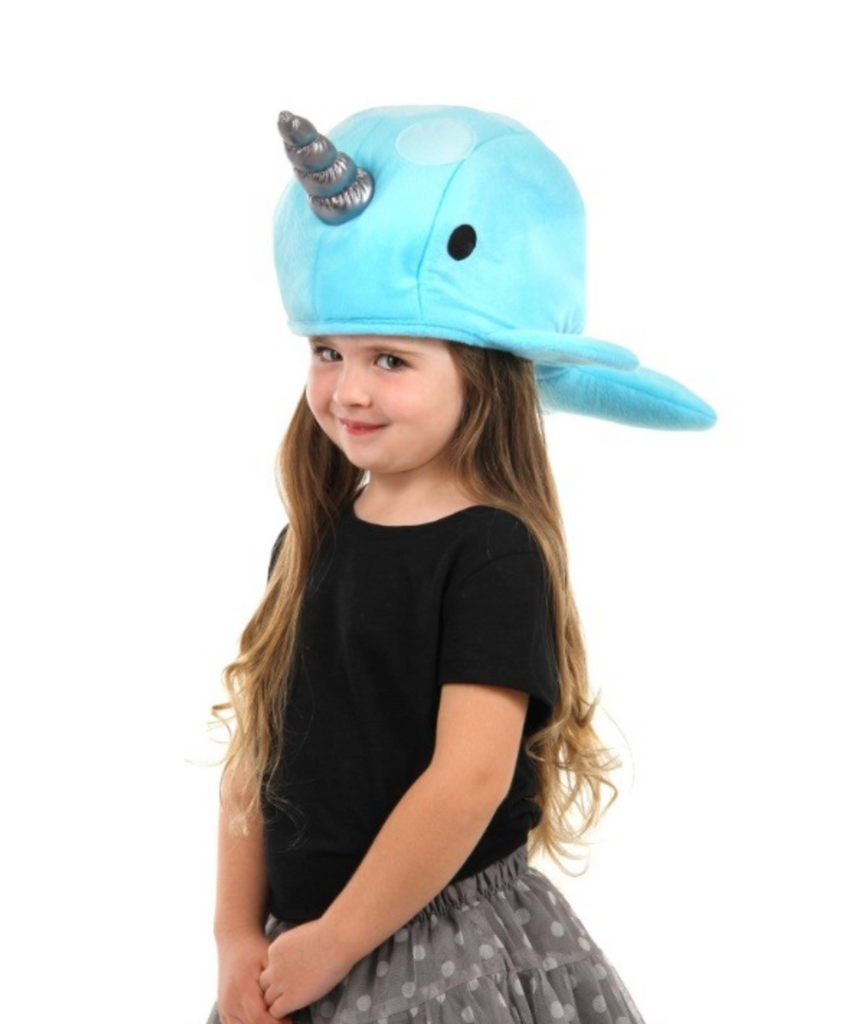 A ong child wearing the blue plush Narwhal Hat with silver horn. 