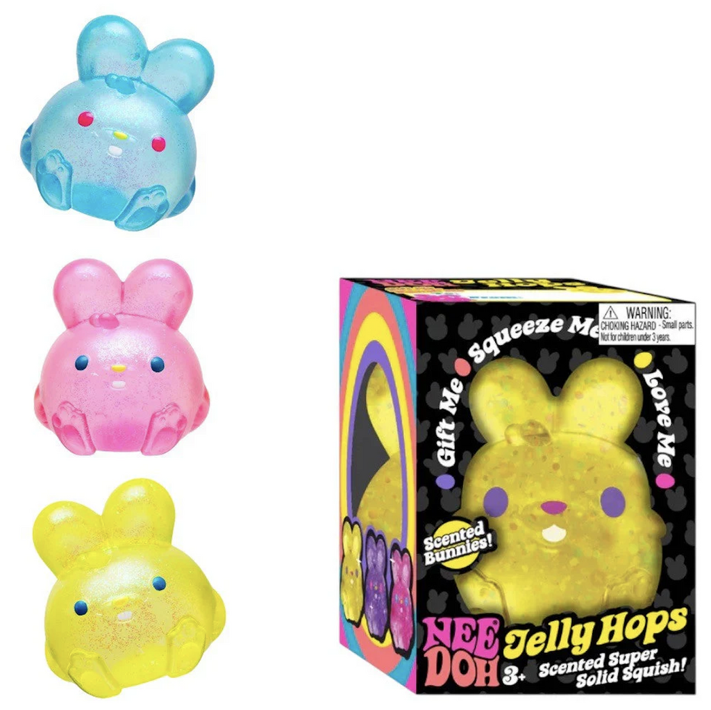 Three NeeDoh Jelly Hops squish bunnies, one blue, one pink and one yellow sitting beside the packaging that is a box with colorful writing and pictures of the squish toys. 