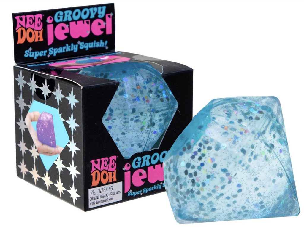 A blue NeeDoh Groovy Jewel super sparkly squish toy shaped like a big diamond set in front of the black box it comes packaged in. 