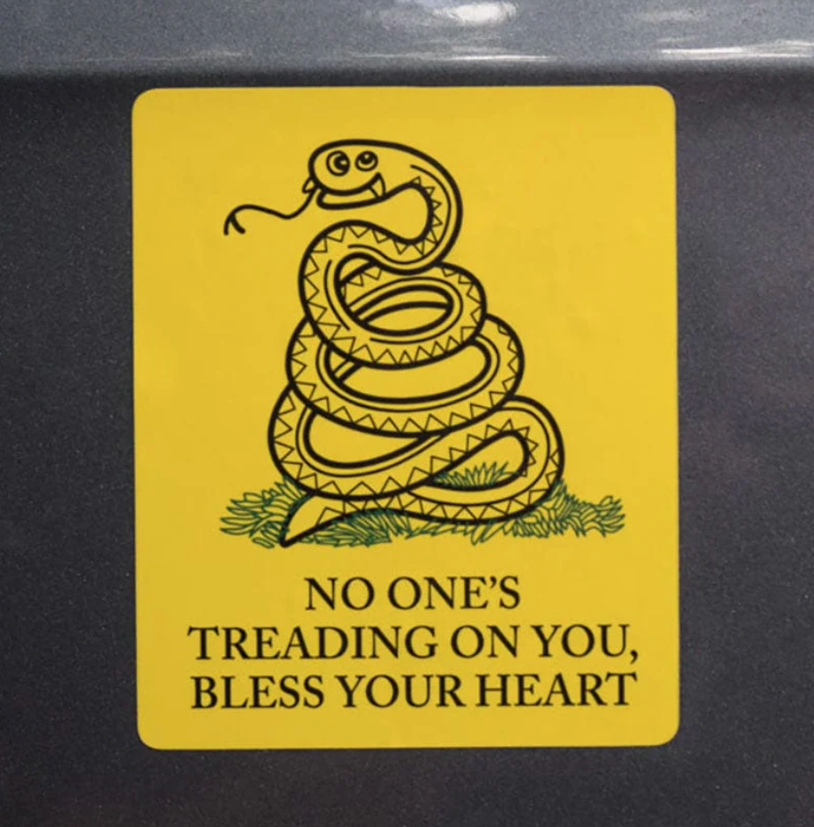 Rectangle, yellow sticker with coiled snake that rtaeds "No one's treading on you, bless your heart" on a car. 